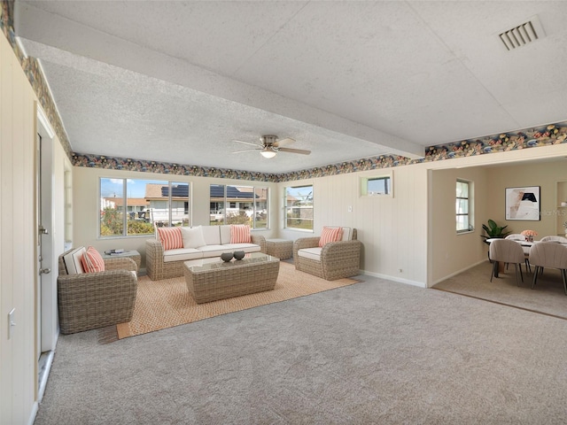 living room featuring a healthy amount of sunlight, carpet flooring, a ceiling fan, and visible vents