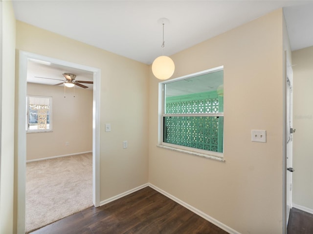 empty room with dark wood-style floors, baseboards, and ceiling fan