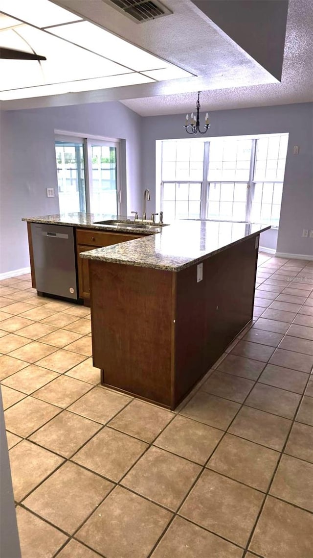 kitchen with a sink, light tile patterned floors, dishwasher, and a textured ceiling
