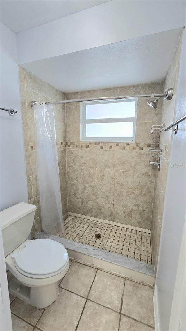 bathroom featuring toilet, tile patterned flooring, and a stall shower