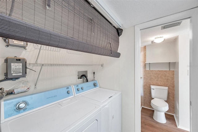 1655 S Highland Ave Unit D140, Clearwater, FL 33756 - clothes washing area featuring washer and dryer, a textured ceiling, light wood-style flooring, and tile walls