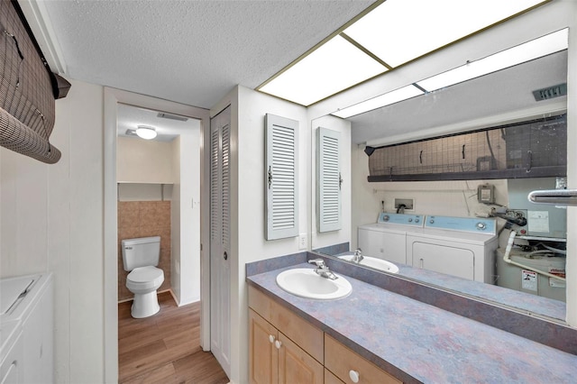 1655 S Highland Ave Unit D140, Clearwater, FL 33756 - bathroom featuring washing machine and clothes dryer, wood finished floors, a closet, toilet, and a textured ceiling