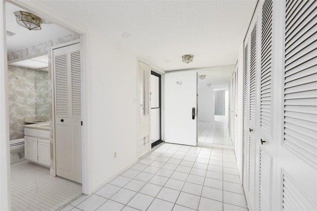 hall featuring wallpapered walls, baseboards, and light tile patterned floors