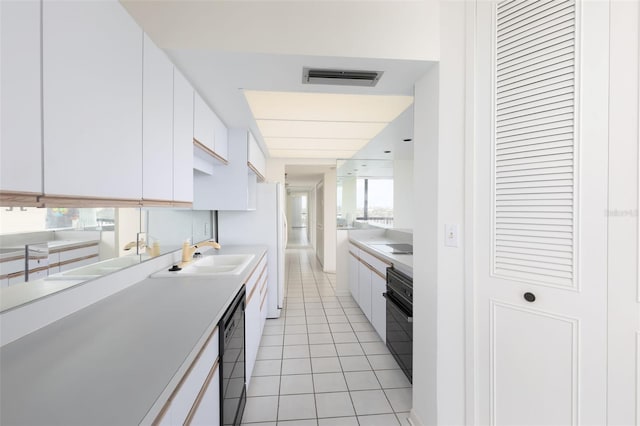 kitchen featuring light countertops, visible vents, light tile patterned floors, a sink, and white cabinetry
