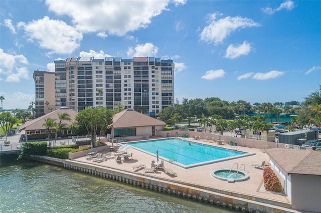 community pool with fence, a water view, and a patio