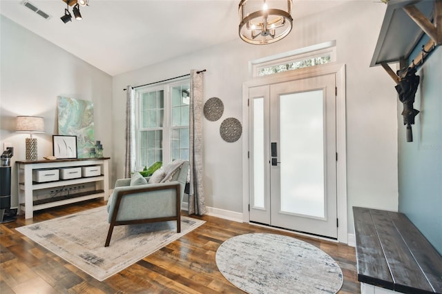 foyer with a chandelier, visible vents, wood finished floors, and lofted ceiling
