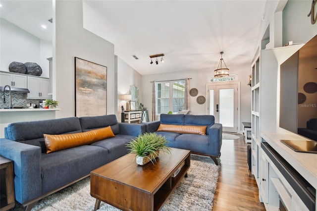 living room with light wood finished floors, visible vents, and vaulted ceiling