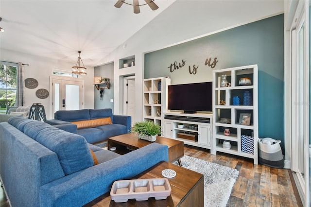 living room with dark wood-type flooring, ceiling fan with notable chandelier, and lofted ceiling