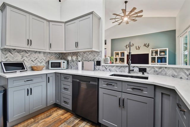 kitchen featuring stainless steel dishwasher, white microwave, a sink, and gray cabinets