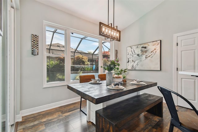 dining area featuring a chandelier, dark wood-style floors, baseboards, and vaulted ceiling