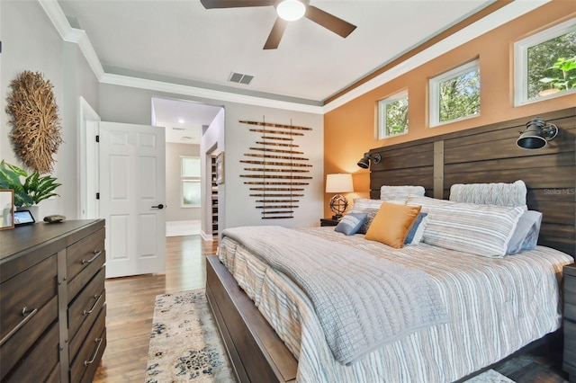 bedroom featuring visible vents, multiple windows, ornamental molding, and wood finished floors