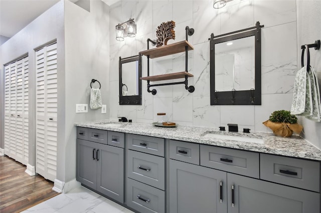 full bathroom with double vanity, marble finish floor, a sink, and baseboards