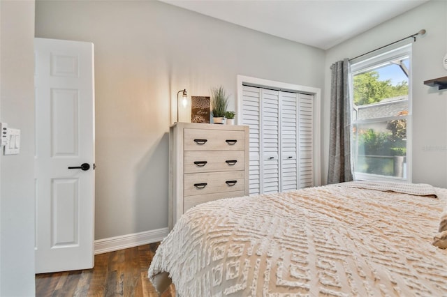 bedroom with dark wood-type flooring, a closet, and baseboards