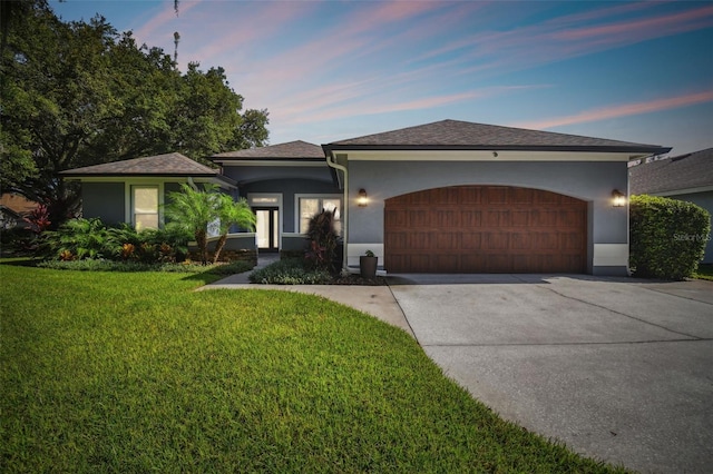 ranch-style home featuring a garage, driveway, stucco siding, and a front lawn