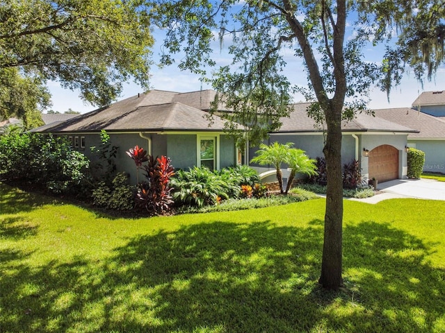 ranch-style house featuring a front yard, concrete driveway, a garage, and stucco siding