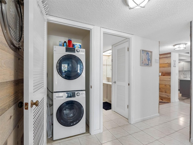 1430 Gulf Blvd Unit 102, Clearwater Beach, FL 33767 - washroom with light tile patterned flooring, stacked washer / dryer, laundry area, and a textured ceiling