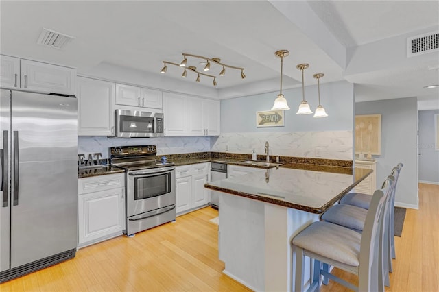 1460 Gulf Blvd Unit 406, Clearwater Beach, FL 33767 - kitchen featuring visible vents, white cabinets, a breakfast bar area, and stainless steel appliances