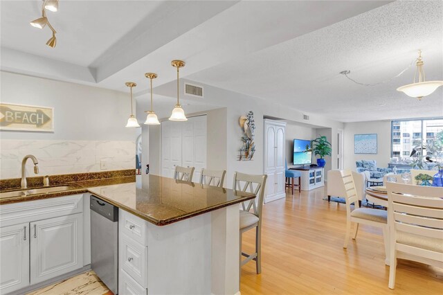 1460 Gulf Blvd Unit 406, Clearwater Beach, FL 33767 - kitchen with visible vents, dishwasher, a sink, white cabinetry, and decorative backsplash
