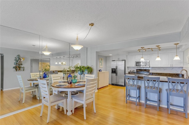 1460 Gulf Blvd Unit 406, Clearwater Beach, FL 33767 - dining room with light wood finished floors, a textured ceiling, and baseboards