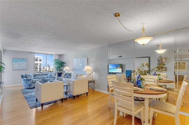 1460 Gulf Blvd Unit 406, Clearwater Beach, FL 33767 - dining room featuring light wood-style floors, a textured ceiling, baseboards, and visible vents