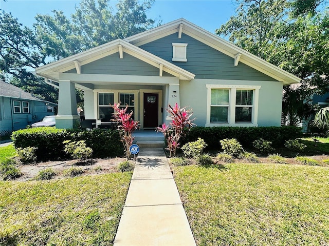 view of front of property with a front yard, a porch, and stucco siding