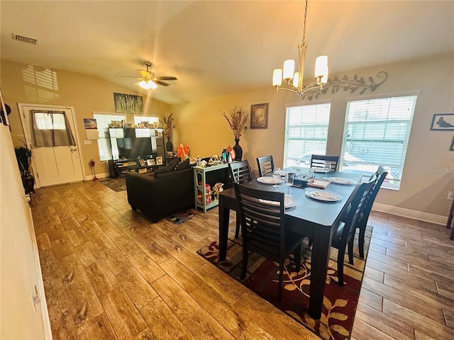dining room featuring baseboards, vaulted ceiling, visible vents, hardwood / wood-style floors, and ceiling fan with notable chandelier