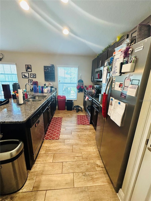 kitchen with dark stone counters, recessed lighting, appliances with stainless steel finishes, a sink, and dark cabinetry