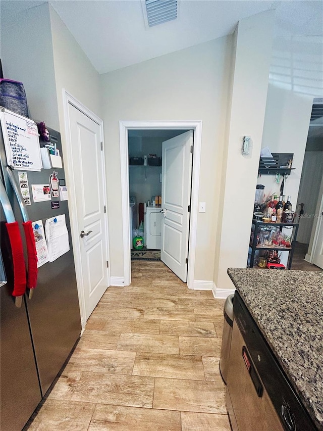 hallway featuring light wood-style floors, baseboards, visible vents, and separate washer and dryer