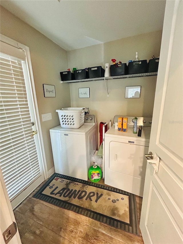 washroom with baseboards, wood finished floors, washer and dryer, and laundry area