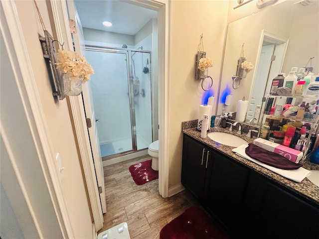 full bath with toilet, a stall shower, wood finished floors, and vanity
