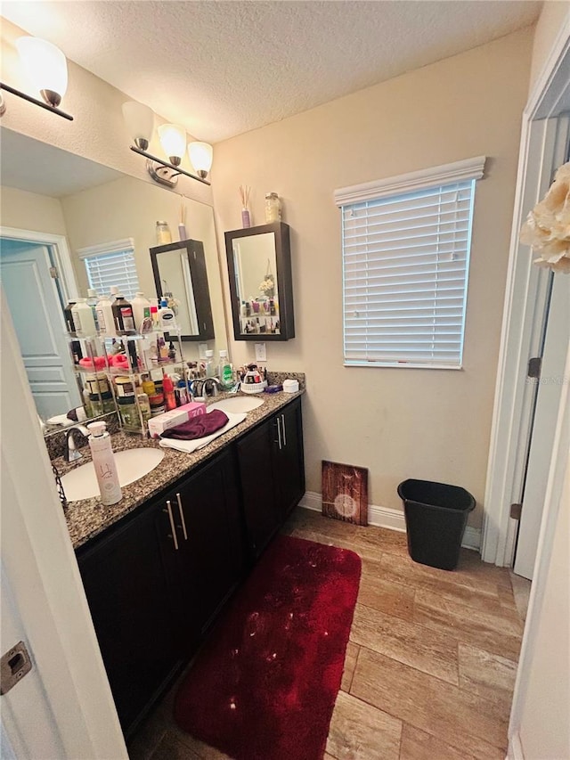 bathroom featuring a sink, double vanity, wood finished floors, and a textured ceiling