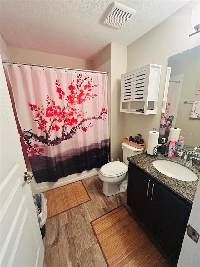 full bath featuring toilet, a textured ceiling, wood finished floors, and visible vents