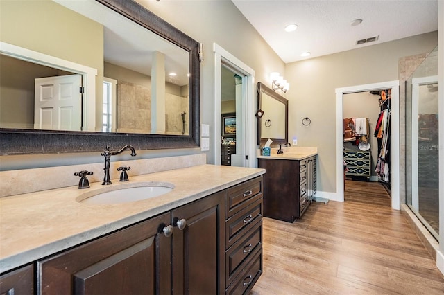25601 Hutcheson Ln, Sorrento, FL 32776 - bathroom featuring wood finished floors, two vanities, a sink, visible vents, and a stall shower