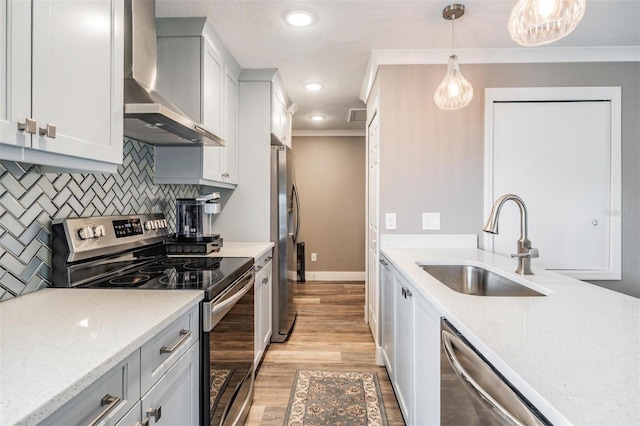 25601 Hutcheson Ln, Sorrento, FL 32776 - kitchen featuring stainless steel appliances, wall chimney range hood, ornamental molding, light wood finished floors, and a sink