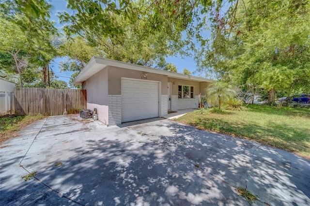 view of front facade with concrete driveway, stucco siding, a front lawn, an attached garage, and fence
