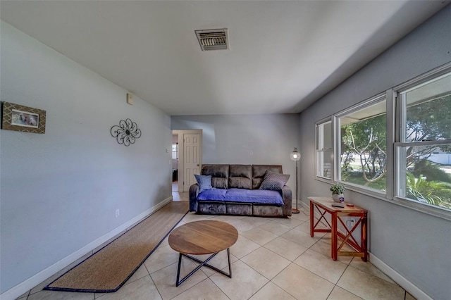 living area featuring light tile patterned floors, visible vents, and baseboards