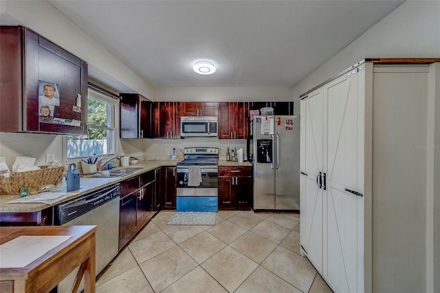kitchen featuring light tile patterned floors, a sink, light countertops, dark brown cabinets, and stainless steel appliances