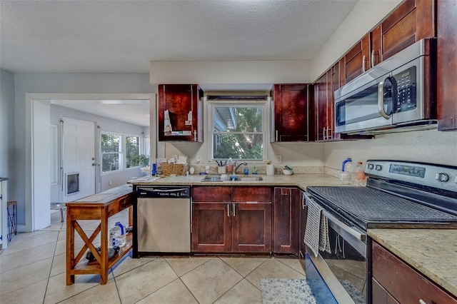 kitchen featuring a sink, dark brown cabinets, appliances with stainless steel finishes, and light tile patterned flooring