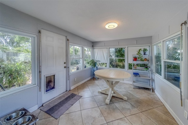 sunroom / solarium featuring baseboards, plenty of natural light, and tile patterned flooring