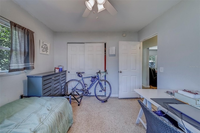 bedroom with a ceiling fan, a closet, multiple windows, and light speckled floor