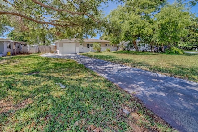 ranch-style house with a garage, a front yard, fence, and aphalt driveway