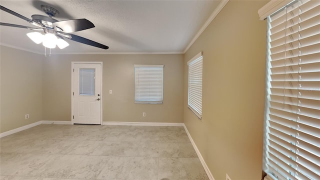 spare room featuring baseboards, crown molding, and ceiling fan