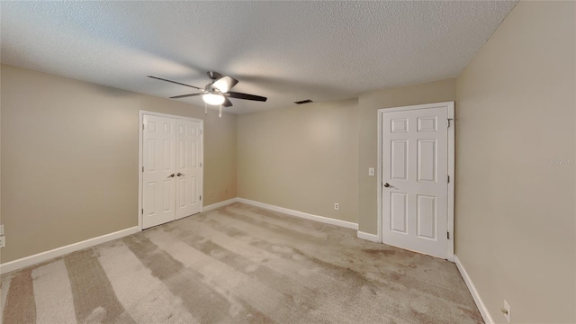 unfurnished bedroom with a closet, carpet flooring, a textured ceiling, and baseboards