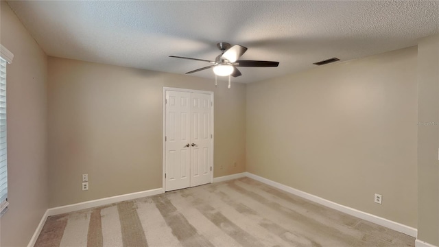 empty room with baseboards, visible vents, light colored carpet, and a ceiling fan