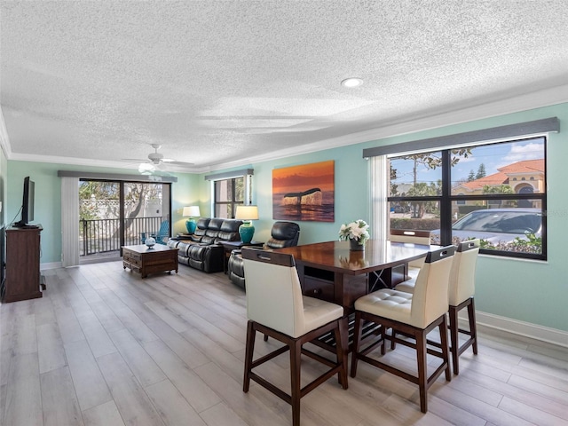 dining space featuring a textured ceiling, light wood finished floors, and ornamental molding