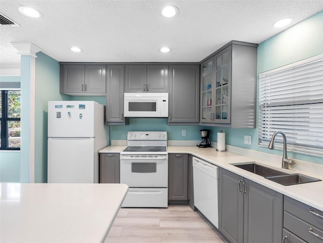 kitchen featuring visible vents, a sink, white appliances, a textured ceiling, and gray cabinets