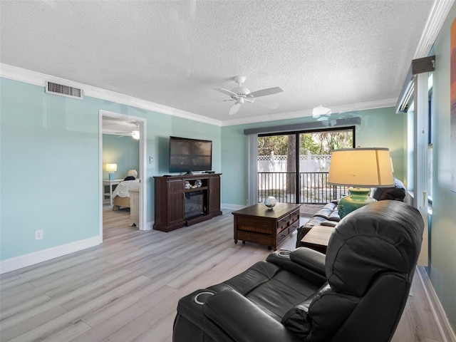 living area with light wood-style flooring, ornamental molding, a ceiling fan, and visible vents