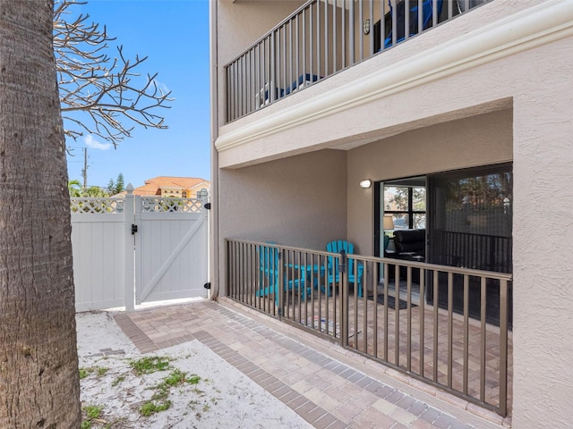 view of patio featuring a balcony, fence, and a gate