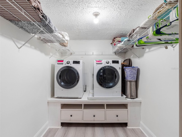 laundry area with laundry area, separate washer and dryer, baseboards, and a textured ceiling