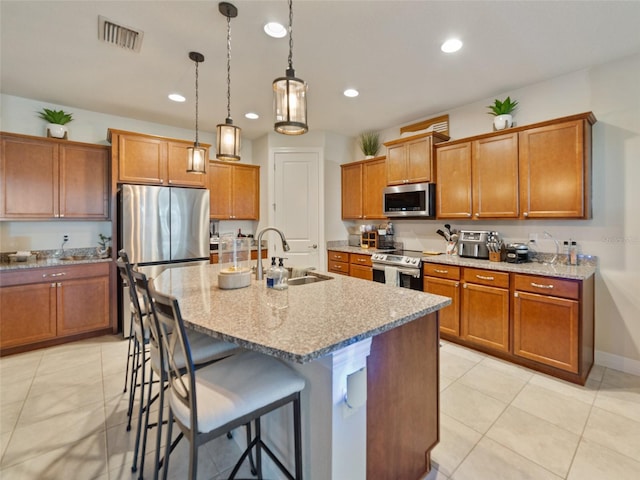 kitchen featuring brown cabinets, appliances with stainless steel finishes, a sink, and visible vents